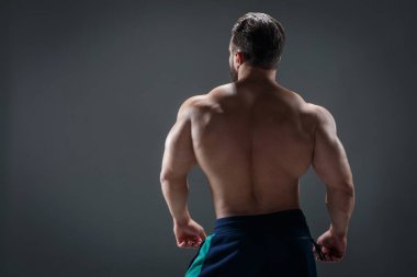 Arka planda çıplak gövdesi olan cesur bir atletik adam arka plandan karanlık bir arka plana bakar..