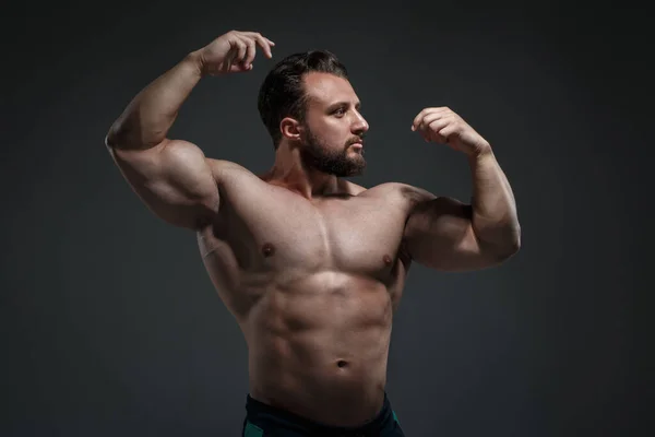 暗い灰色の背景に隔離された筋肉を示す裸の胴を持つ若い運動選手の肖像画 — ストック写真