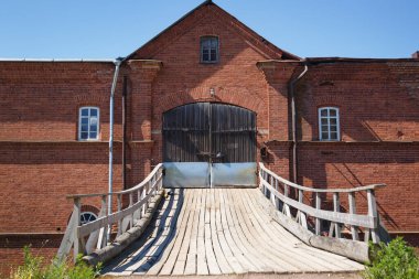 Güneşli bir yaz gününde eski bir kırmızı tuğladan kalenin kapılarına açılan tahta bir köprü..