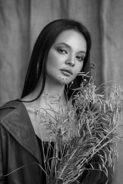 Güzel bir kızın siyah-beyaz portresi doğal makyajlı ve bir buket çivili.