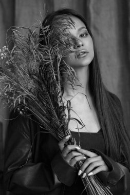 Güzel bir kızın siyah-beyaz portresi doğal makyajlı ve bir buket çivili.