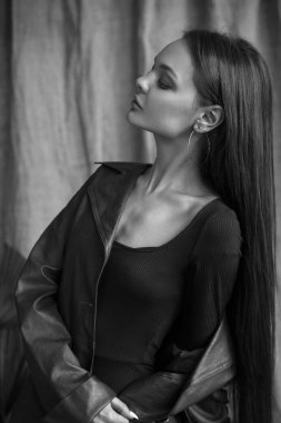 Stüdyoda deri ceketli, doğal makyajlı güzel bir kızın siyah beyaz bir portresi..