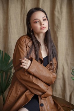 Stüdyoda deri kahverengi ceketli, doğal makyajlı güzel bir kızın moda portresi..
