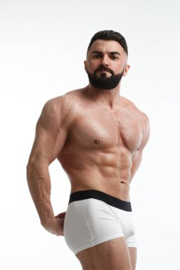 Beyaz arka planda çıplak gövdesi olan atletik sakallı bir adam..