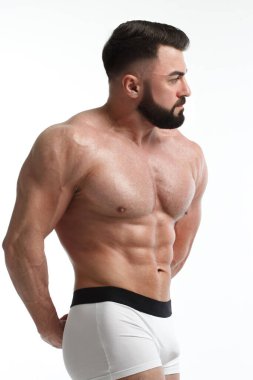 Beyaz arka planda çıplak gövdesi olan atletik sakallı bir adam..