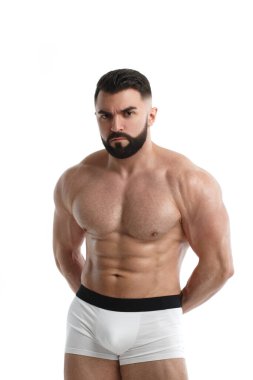 Atletik sakallı, kolları arkada katlanmış, beyaz arka planda soyutlanmış kaslı bir adam..