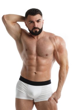 Atletik sakallı, çıplak kaslı bir adam bir eli başının arkasında, diğer eli aşağıda, beyaz bir arka planda izole halde..