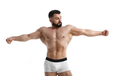 Atletik sakallı bir adam çıplak kaslı gövdesiyle kollarını yana açmış beyaz arka planda izole edilmiş..