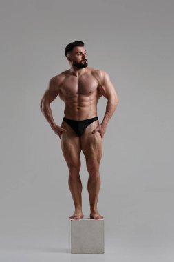 Genç kaslı atletik adam gri arka planda izole edilmiş..