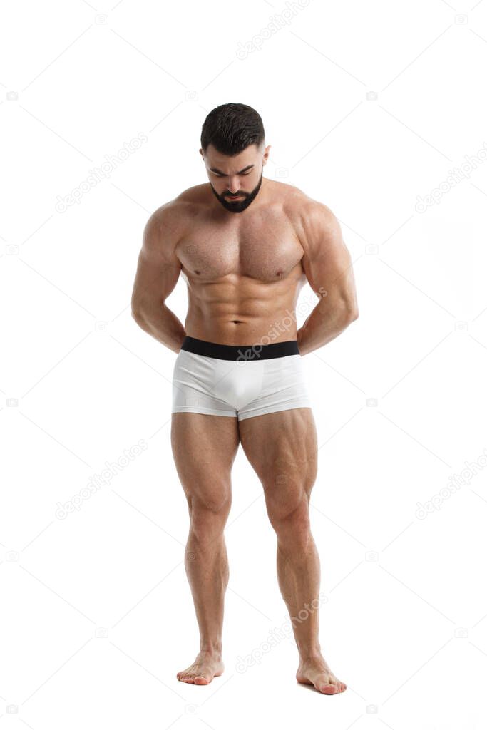 Athletic bearded man with a naked muscular torso with his arms folded behind his back stands in full growth isolated on a white background.