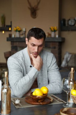 Çok şaşırmış yakışıklı bir adam yemek masasında limonlu bir tabağın üzerinde oturuyor..