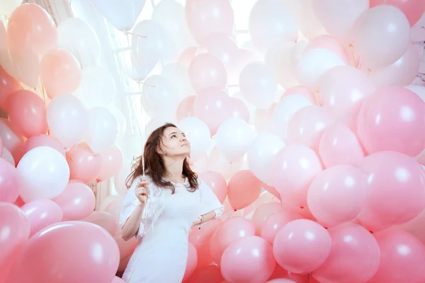 Meisje in witte vliegen onder roze ballonnen — Stockfoto