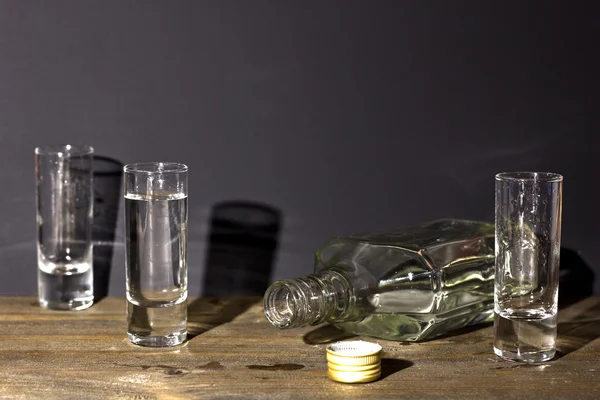 แก้วที่มีขวดวอดก้าบนโต๊ะ — ภาพถ่ายสต็อก