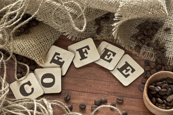 Flavored coffee beans spilled out of the bag on a wooden table — Stock Photo, Image