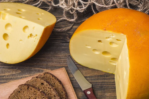 Rueda de queso en rodajas en una mesa de madera — Foto de Stock