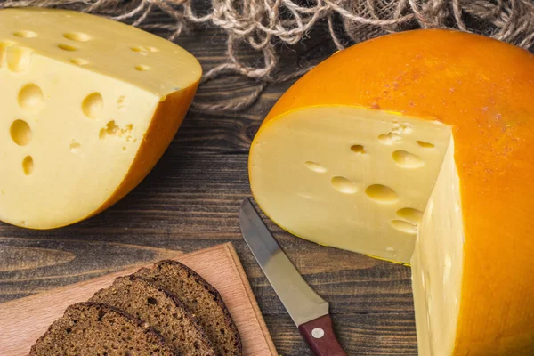 Sliced cheese wheel on a wooden table — Stock Photo, Image