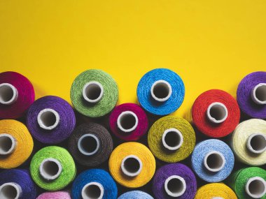 Sarı arka planda dikiş ve nakış işlemek için çok renkli iplikler