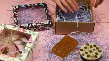 El yapımı güzellik ürünlerinin paketlenmesi. Kişi karton kutuya doğal sabun kalıpları koyuyor. Banyo ürünlerinin daha sonra satışı için paketlenmesi