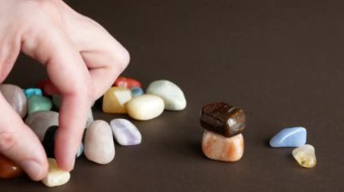 Kişi, pürüzsüz taşlardan oluşan bir piramit oluşturuyor. Renkli değerli taşlar yığını.