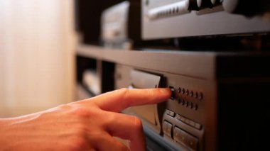 Disk tepsisini açmak için bir düğmeye basılıyor, CD diskini yerleştirip oynatma düğmesine basılıyor. Bir CD oynatıcıyla müzik dinlemek