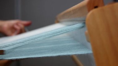 Yandan dokuma işlemi, yakın çekim. Mekik çapraz iplikleri uzunlamasına iplikçiklerin arasından taşıyor. Odaklanma detayları