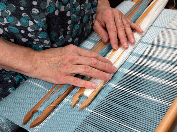 Weaver 'ın elleri ve iki mekik el dokuma tezgahında yatıyor. Çizgili kumaştan el dokuması. İş molası kavramı