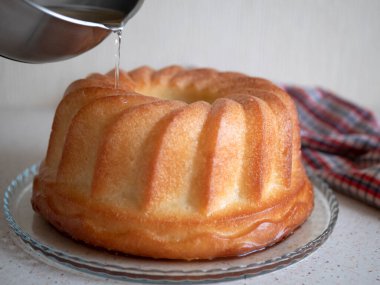 Taze pişmiş romlu baba. Şerbeti Savarin 'in üzerine döküyorum. Rom kaplı dairesel pasta.