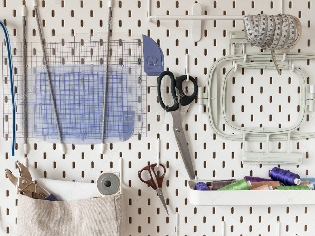 White pegboard with sewing supplies. Concept of tailoring and needlework, ergonomic storage