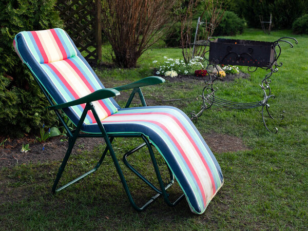 Chaise longue and alit coals in chargrill. In expectation of barbecue. Idyllic landscape