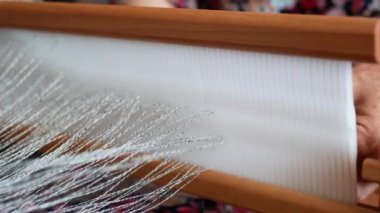 Dokuma tezgahını bükme işlemi. Heddle kancası beliriyor, keten ipliğini yakalıyor ve yuvadan sazlığın gözüne bağlıyor.