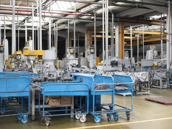 Fabrika zemininin kapalı ortamında. Üzerinde metal atölyeler olan mavi vagonlar, atölyede endüstriyel birimler. Üretim atölyesi