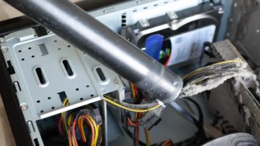 Elektrik süpürgesiyle elektrik kablolarındaki tozu kaldırıyorum. Sistem birimi davasının bileşenlerinin tozunu alıyorum. Birisi bilgisayarın içini temizliyor.