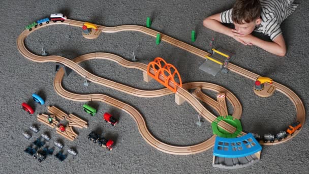 男孩在玩玩具铁路 正在观看火车撞车事故 八岁的男孩在玩木制火车模型 顶部视图 — 图库视频影像