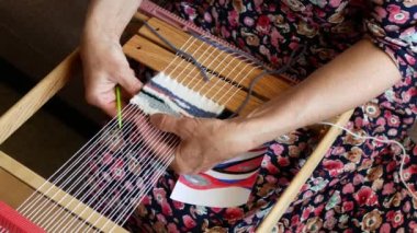 Weaver çizmek için küçük bir duvar halısı yapıyor. Örgü dokuma. Zanaatkarın elleri iş başında, yakın çekim.