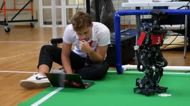 ミンスク ベラルーシ 2021年8月27日 人は床に座って ラップトップでサッカーロボットをプログラミングしています — ストック動画