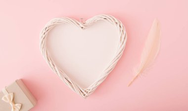 Yaratıcı kopya alanı, hediye kutusu ve tüyü olan kalp şekli. Pembe renk. Düz katman..