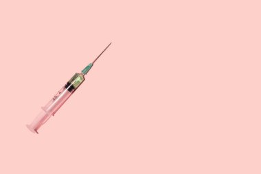 Pastel pembe arka planda bir şırınga. (Coronavirus aşısı) Uzayı kopyala