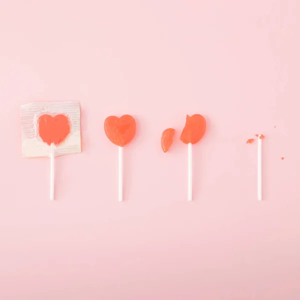 4 heart-shaped lollipops on a pastel pink background.Minimal flat lay concept.