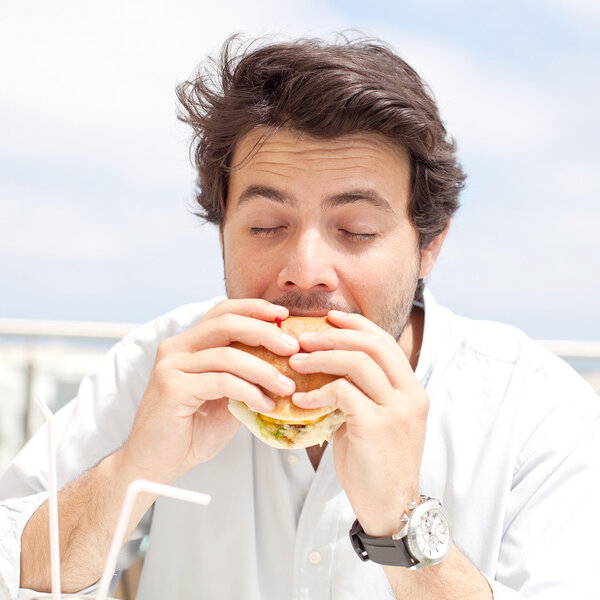 Молодой человек ест гамбургер
