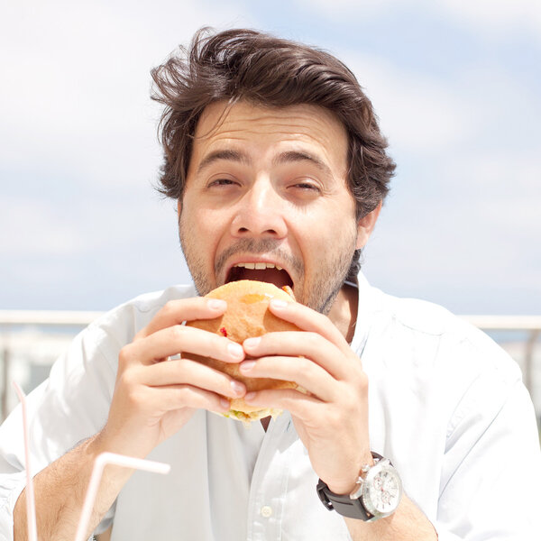 Молодой человек ест гамбургер
