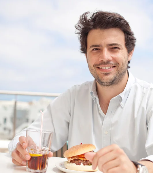 Genç adam bir hamburguer yeme — Stok fotoğraf