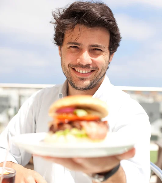 Genç adam bir hamburguer yeme — Stok fotoğraf