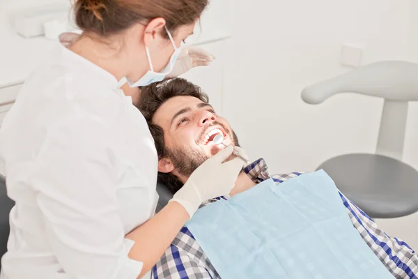 Joven feliz hombre y mujer en un examen dental en el dentista — Foto de Stock