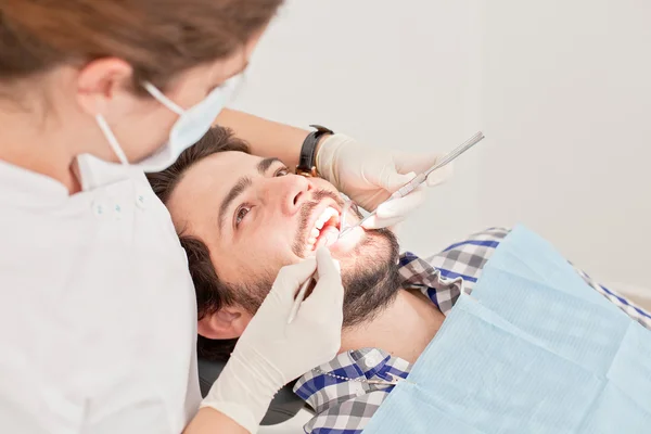 Joven feliz hombre y mujer en un examen dental en el dentista —  Fotos de Stock