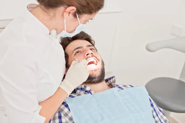 Glad ung man och kvinna i en dental undersökning hos tandläkare — Stockfoto
