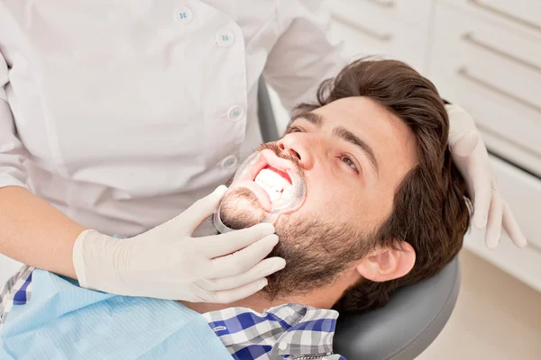 Joven feliz hombre y mujer en un examen dental en el dentista —  Fotos de Stock