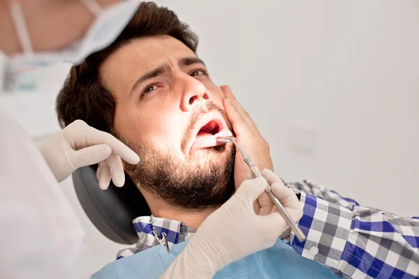 Joven hombre y mujer en un examen dental en el dentista —  Fotos de Stock