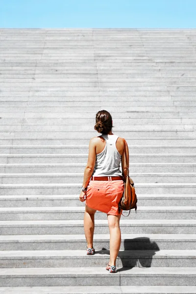 Young woman going upstairs. Challenge metaphor.