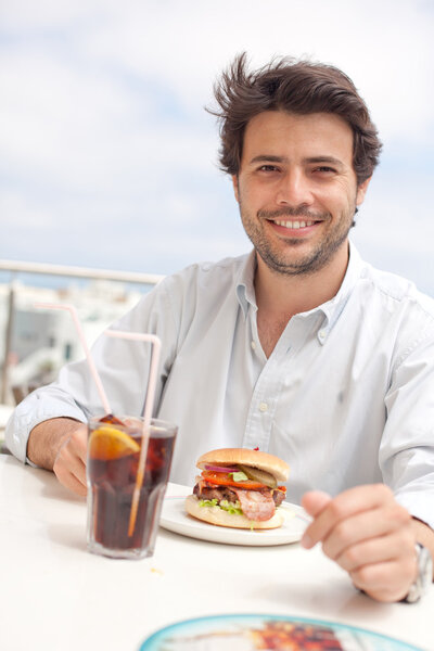 Молодой человек ест гамбургер
