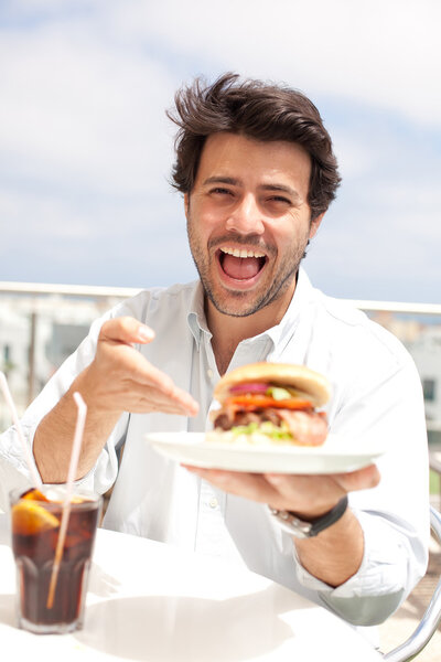 Молодой человек ест гамбургер
